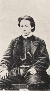 Hijikata Toshizō assis en tenue occidentale, sur une photographie ancienne.